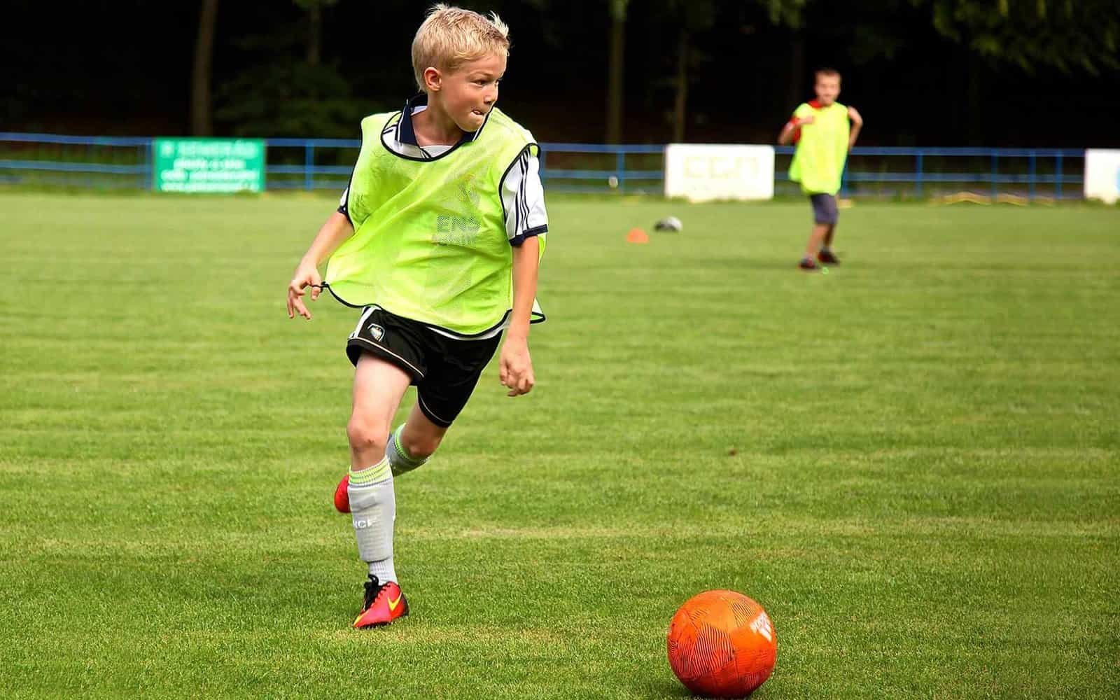 Youth soccer training at Osaro Intl Sports Academy, kids developing skills on a lush green field.