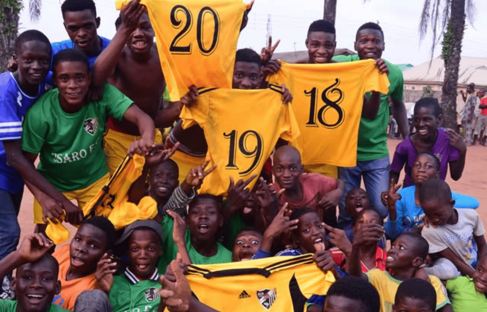 Osaro Intl Sports Academy youth football team celebrating victory with yellow jerseys in outdoor setting.