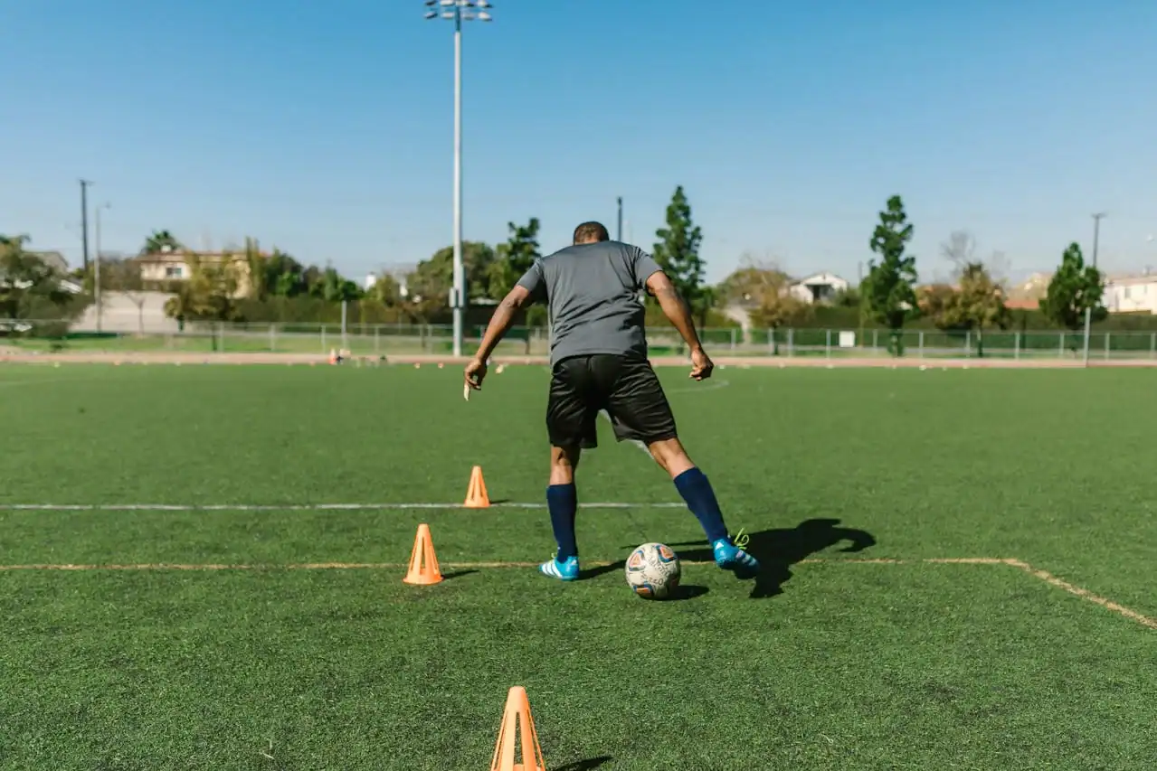 Football training at Osaro Intl Sports Academy. Soccer player practicing dribbling skills on a green field during training session.